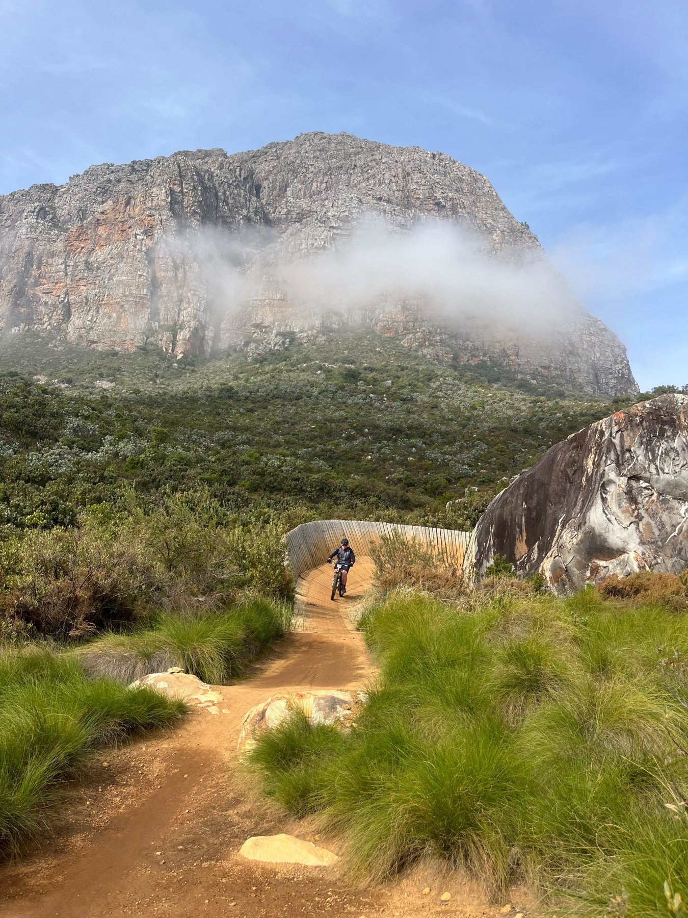 Mountain biker riding singletrack beneath a granite rock face in the Stellenbosch mountains
